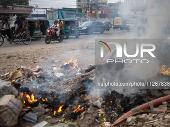 People are moving past burning garbage and plastic trash beside a busy road in Dhaka, Bangladesh, on May 23, 2024. Dhaka's air quality is be...