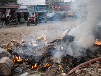 People are moving past burning garbage and plastic trash beside a busy road in Dhaka, Bangladesh, on May 23, 2024. Dhaka's air quality is be...