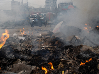 People are moving past burning garbage and plastic trash beside a busy road in Dhaka, Bangladesh, on May 23, 2024. Dhaka's air quality is be...