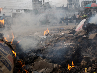 People are moving past burning garbage and plastic trash beside a busy road in Dhaka, Bangladesh, on May 23, 2024. Dhaka's air quality is be...