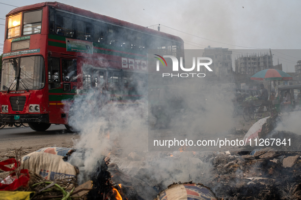 People are moving past burning garbage and plastic trash beside a busy road in Dhaka, Bangladesh, on May 23, 2024. Dhaka's air quality is be...