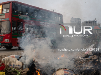 People are moving past burning garbage and plastic trash beside a busy road in Dhaka, Bangladesh, on May 23, 2024. Dhaka's air quality is be...