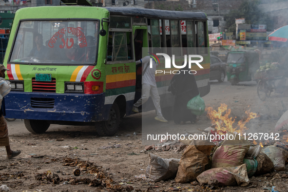 People are moving past burning garbage and plastic trash beside a busy road in Dhaka, Bangladesh, on May 23, 2024. Dhaka's air quality is be...