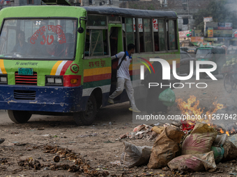 People are moving past burning garbage and plastic trash beside a busy road in Dhaka, Bangladesh, on May 23, 2024. Dhaka's air quality is be...