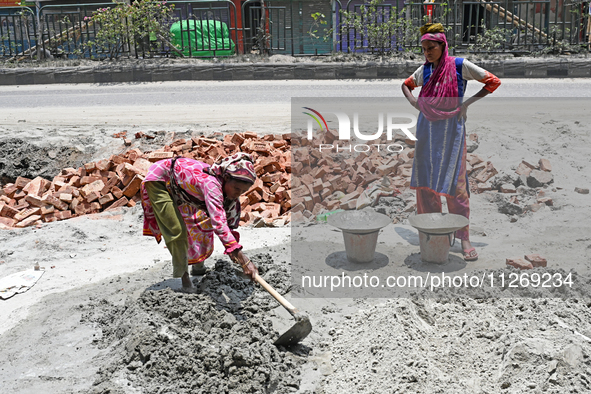 Women daily laborers work at a road construction site in Dhaka, Bangladesh, on May 24, 2024. 