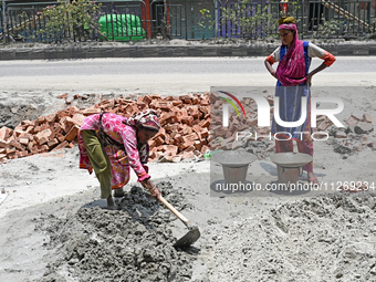 Women daily laborers work at a road construction site in Dhaka, Bangladesh, on May 24, 2024. (