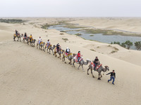 Tourists are experiencing camel riding and desert scenery at Luoburen Village Scenic Area in Bazhou, China, on May 24, 2024. (