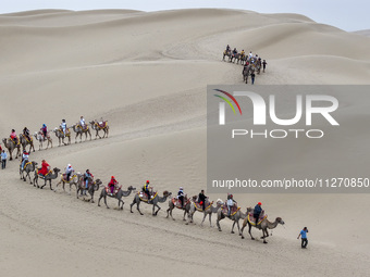 Tourists are experiencing camel riding and desert scenery at Luoburen Village Scenic Area in Bazhou, China, on May 24, 2024. (