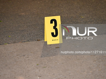 Crime scene investigators are marking shell casings and other evidence at the scene of a shooting where one person is killed and one person...