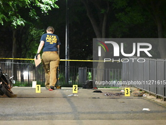 Crime scene investigators are marking shell casings and other evidence at the scene of a shooting where one person is killed and one person...