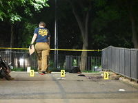 Crime scene investigators are marking shell casings and other evidence at the scene of a shooting where one person is killed and one person...