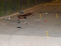 Crime scene investigators are marking shell casings and other evidence at the scene of a shooting where one person is killed and one person...