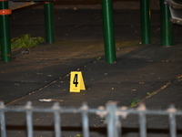 Crime scene investigators are marking shell casings and other evidence at the scene of a shooting where one person is killed and one person...