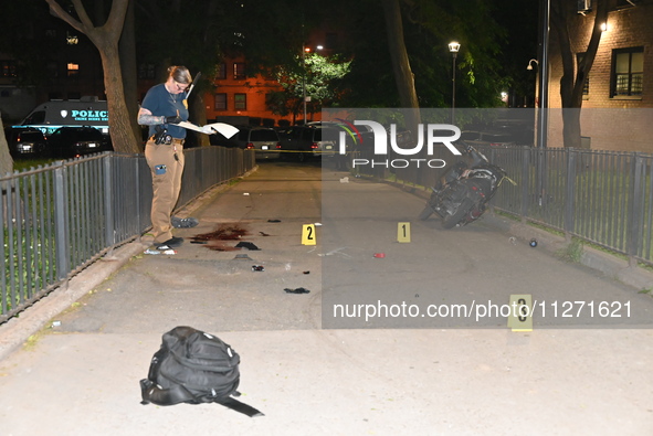 Crime scene investigators are marking shell casings and other evidence at the scene of a shooting where one person is killed and one person...