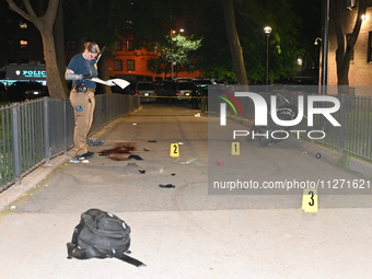 Crime scene investigators are marking shell casings and other evidence at the scene of a shooting where one person is killed and one person...