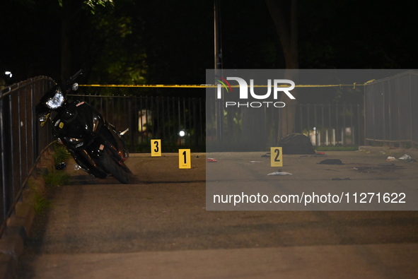 Crime scene investigators are marking shell casings and other evidence at the scene of a shooting where one person is killed and one person...