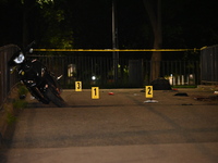 Crime scene investigators are marking shell casings and other evidence at the scene of a shooting where one person is killed and one person...