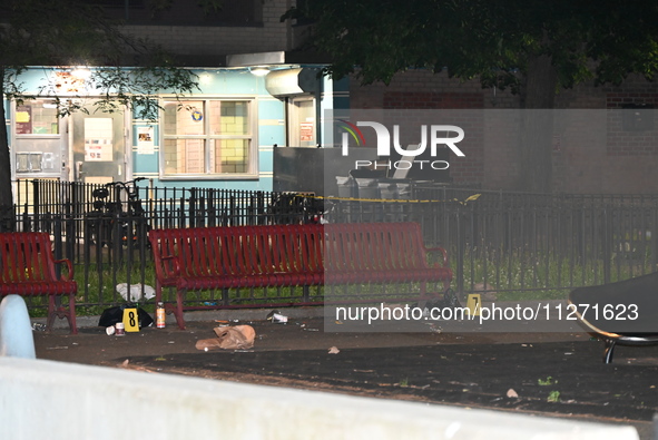 Crime scene investigators are marking shell casings and other evidence at the scene of a shooting where one person is killed and one person...