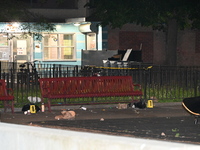 Crime scene investigators are marking shell casings and other evidence at the scene of a shooting where one person is killed and one person...