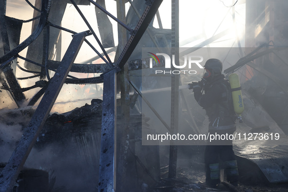 A rescuer is putting out a fire at an Epicentr K construction supermarket hit with two Russian glide bombs in Kharkiv, Ukraine, on May 25, 2...