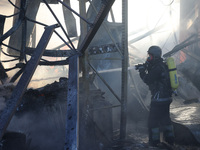 A rescuer is putting out a fire at an Epicentr K construction supermarket hit with two Russian glide bombs in Kharkiv, Ukraine, on May 25, 2...