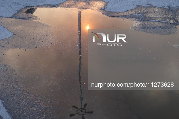 The sun is reflecting in a puddle outside an Epicentr K construction supermarket hit with two Russian glide bombs in Kharkiv, Ukraine, on Ma...