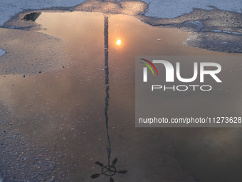 The sun is reflecting in a puddle outside an Epicentr K construction supermarket hit with two Russian glide bombs in Kharkiv, Ukraine, on Ma...