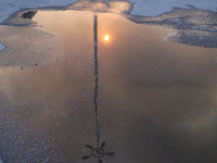 The sun is reflecting in a puddle outside an Epicentr K construction supermarket hit with two Russian glide bombs in Kharkiv, Ukraine, on Ma...