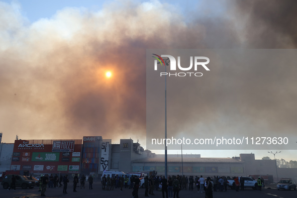 The sun is being seen through smoke rising over an Epicentr K construction supermarket hit with two Russian glide bombs in Kharkiv, Ukraine,...