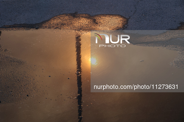 The sun is reflecting in a puddle outside an Epicentr K construction supermarket hit with two Russian glide bombs in Kharkiv, Ukraine, on Ma...