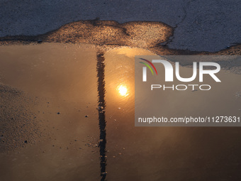 The sun is reflecting in a puddle outside an Epicentr K construction supermarket hit with two Russian glide bombs in Kharkiv, Ukraine, on Ma...