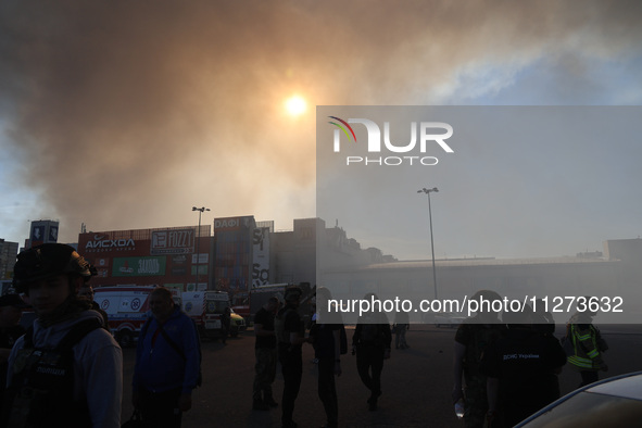 The sun is being seen through smoke rising over an Epicentr K construction supermarket hit with two Russian glide bombs in Kharkiv, Ukraine,...