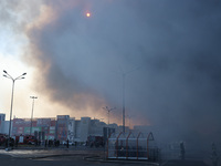 The sun is being seen through smoke rising over an Epicentr K construction supermarket hit with two Russian glide bombs in Kharkiv, Ukraine,...