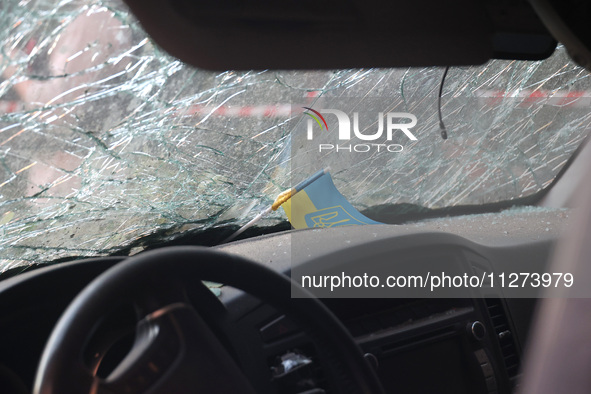 A Ukrainian miniature flag is sitting on the dashboard under the cracked windscreen of a car damaged in a Russian missile strike in central...