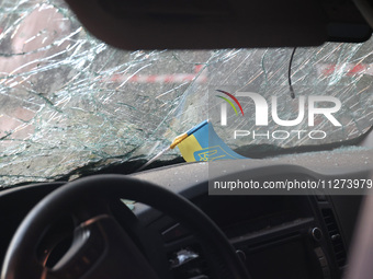 A Ukrainian miniature flag is sitting on the dashboard under the cracked windscreen of a car damaged in a Russian missile strike in central...