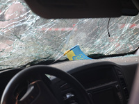 A Ukrainian miniature flag is sitting on the dashboard under the cracked windscreen of a car damaged in a Russian missile strike in central...