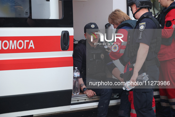 A paramedic is giving first aid to a police officer at an office building destroyed by a Russian missile strike in central Kharkiv, Ukraine,...