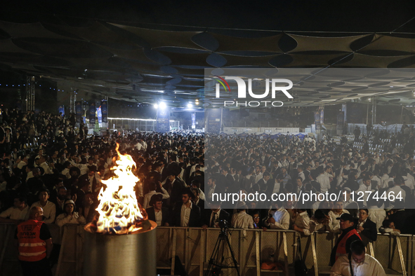 Ultra-Orthodox Jewish men watch a fire burn as they celebrate the Jewish holiday of Lag BaOmer in the Sheikh Jarrah neighborhood of Israeli-...