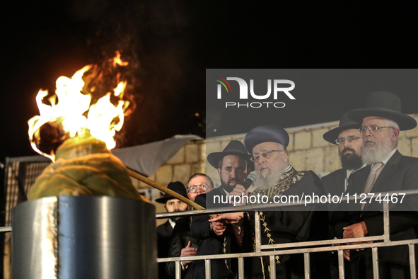 Ultra-Orthodox Jewish men watch a fire burn as they celebrate the Jewish holiday of Lag BaOmer in the Sheikh Jarrah neighborhood of Israeli-...