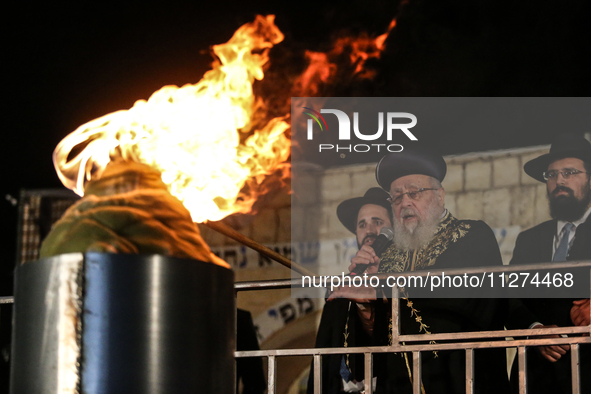 Ultra-Orthodox Jewish men watch a fire burn as they celebrate the Jewish holiday of Lag BaOmer in the Sheikh Jarrah neighborhood of Israeli-...