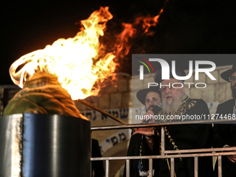 Ultra-Orthodox Jewish men watch a fire burn as they celebrate the Jewish holiday of Lag BaOmer in the Sheikh Jarrah neighborhood of Israeli-...