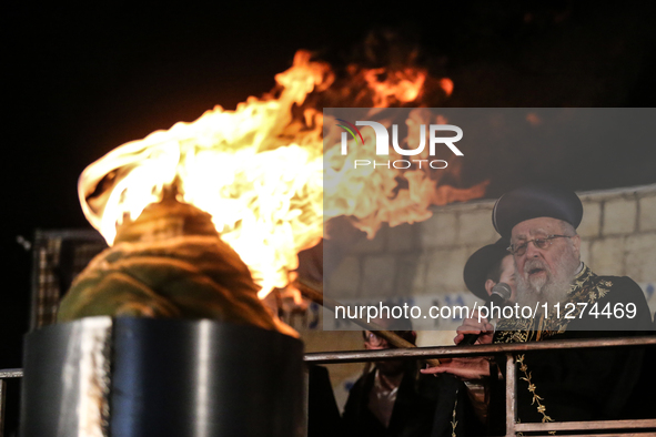 Ultra-Orthodox Jewish men watch a fire burn as they celebrate the Jewish holiday of Lag BaOmer in the Sheikh Jarrah neighborhood of Israeli-...