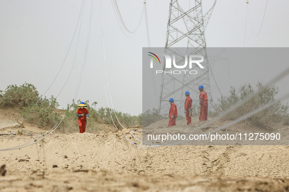 Construction workers are erecting a power grid at the Bazhou-Tieganlik-Ruoqiang 750 kV transmission line project site in Korla, China, on Ma...