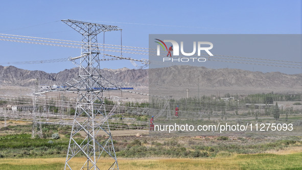 Construction workers are erecting a power grid at a height at the Bazhou-Tieganlik-Ruoqiang 750 kV transmission line project site in Korla,...