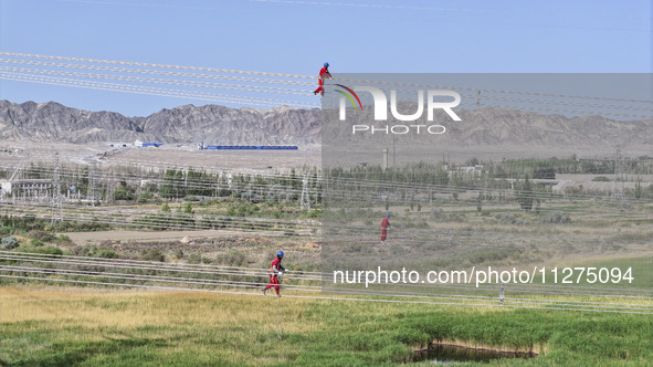 Construction workers are erecting a power grid at a height at the Bazhou-Tieganlik-Ruoqiang 750 kV transmission line project site in Korla,...