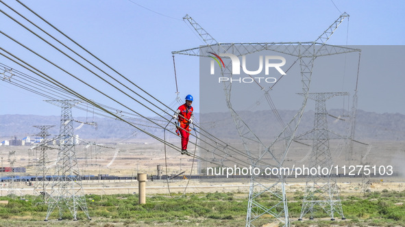 Construction workers are erecting a power grid at a height at the Bazhou-Tieganlik-Ruoqiang 750 kV transmission line project site in Korla,...