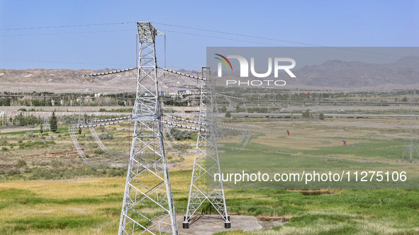 Construction workers are erecting a power grid at a height at the Bazhou-Tieganlik-Ruoqiang 750 kV transmission line project site in Korla,...