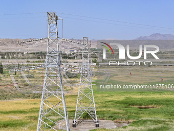 Construction workers are erecting a power grid at a height at the Bazhou-Tieganlik-Ruoqiang 750 kV transmission line project site in Korla,...