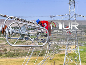 Construction workers are erecting a power grid at a height at the Bazhou-Tieganlik-Ruoqiang 750 kV transmission line project site in Korla,...