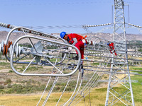 Construction workers are erecting a power grid at a height at the Bazhou-Tieganlik-Ruoqiang 750 kV transmission line project site in Korla,...